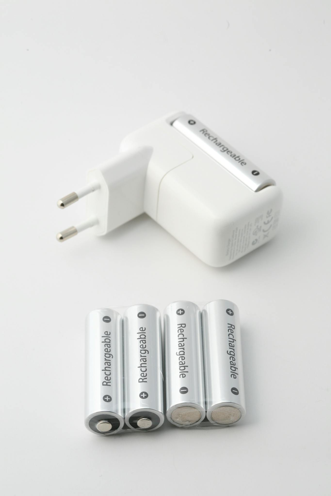 Close-up of a battery charger and rechargeable batteries on a white background, perfect for tech and energy themes.