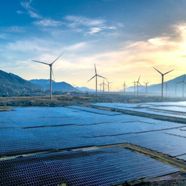 Stunning landscape featuring solar panels and wind turbines at sunrise, symbolizing sustainable energy.