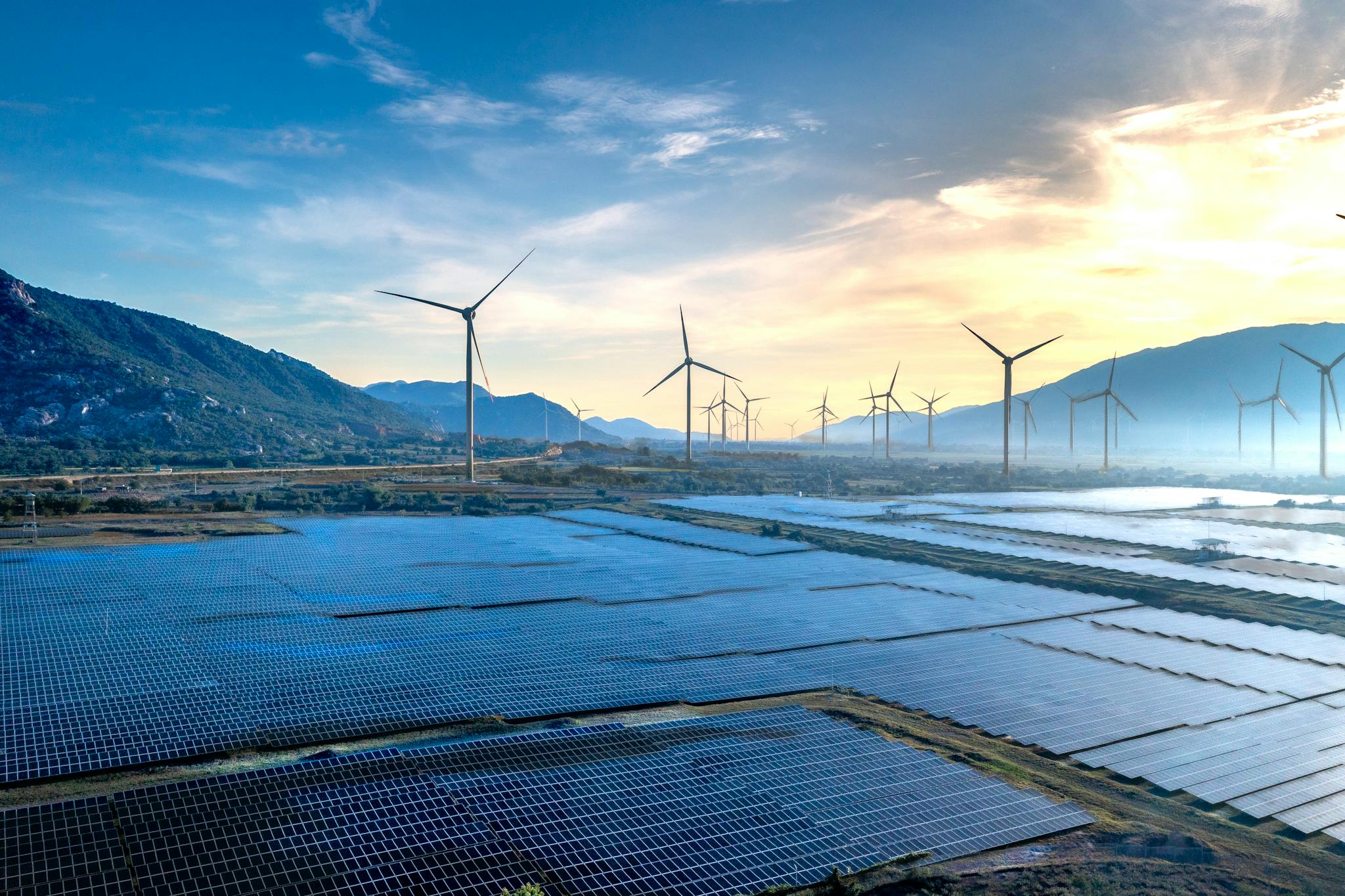 Stunning landscape featuring solar panels and wind turbines at sunrise, symbolizing sustainable energy.