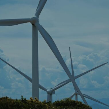 Wind turbines in a lush landscape under blue skies, symbolizing sustainable energy.