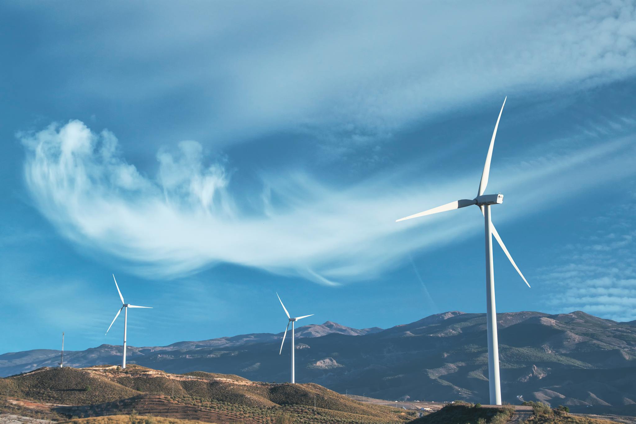 Wind turbines on a hillside capturing clean energy under a serene blue sky.
